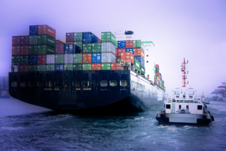 Container ship being escorted into Hong Kong by a tugboat