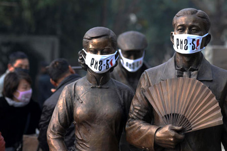 Wuhan pollution protests - statues wear masks with airborne particulate matter readings