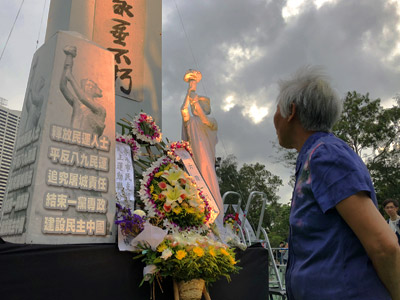 4 June 2018 rally: a lady pauses reverentially before a memorial at Victoria Park, Hong Kong