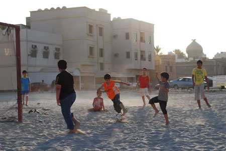 Football and politics in Middle East - kids play soccer in manama, bahrain sands